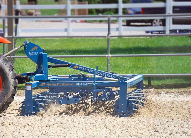 blue Premier Groomer behind a tractor