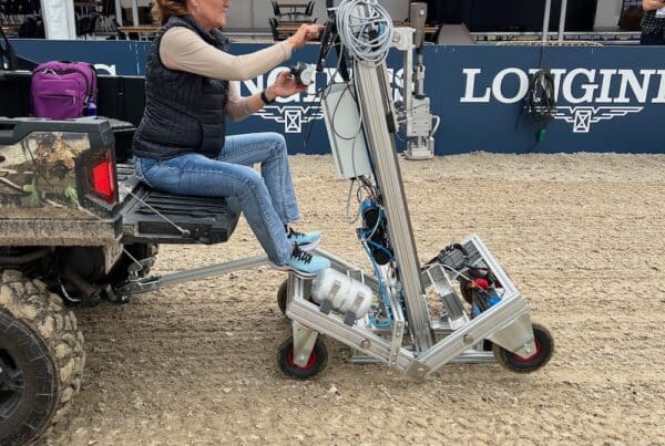 Woman sitting on tractor using tool to test horse footing product