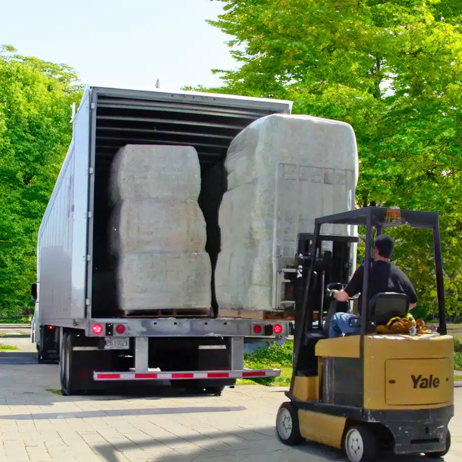 forklift offloading a shipment of footing bales